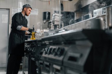 Otel restoranındaki profesyonel mutfak şefi hamburgerin üstünde köfte pişiriyor.