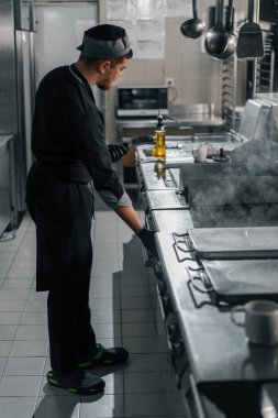 Otel restoranındaki profesyonel mutfak şefi hamburgerin üstünde köfte pişiriyor.