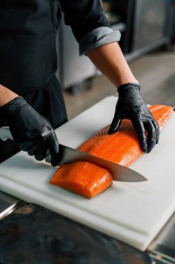 Otel restoranındaki profesyonel mutfak şefi büyük taze bir somon leşini bıçakla keser.