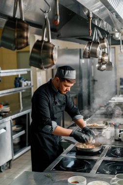 Otel restoranında profesyonel mutfak. Şef tavada deniz ürünleri kızartıyor.