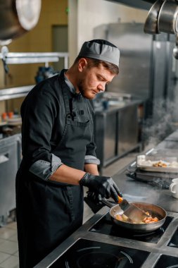 Otel restoranında profesyonel mutfak. Şef tavada deniz ürünleri kızartıyor.