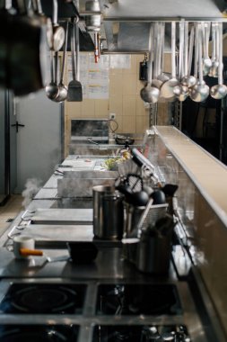 Otel restoranındaki profesyonel mutfak kepçeleri kaputta asılı.