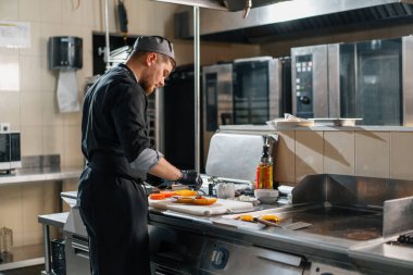 Otel restoranında profesyonel mutfak. Şef hamburgerin malzemelerini hazırlıyor.