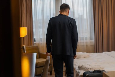 Bavullu bir adam uçuştan sonra bir otel odasına girer.