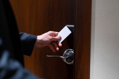 Elinde bavul olan bir adam otel odasının kapısını açıyor. Seyahat konsepti olan bir iş adamı.