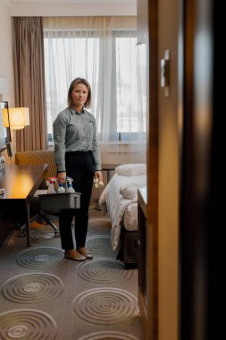 Otel temizlikçisinin temizlik odaları deterjan konsepti olan temizlik sepetleri taşır.