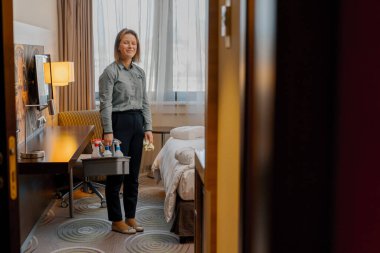 Otel temizlikçisinin temizlik odaları deterjan konsepti olan temizlik sepetleri taşır.