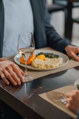 Otel restoranında bir randevu, somonlu bir kadeh şarap risotto ve yakın plan masa ıspanağı.