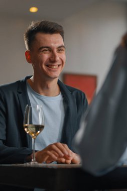 Otel restoranında bir adamla bir kadın yakın planda beyaz şarap içer.