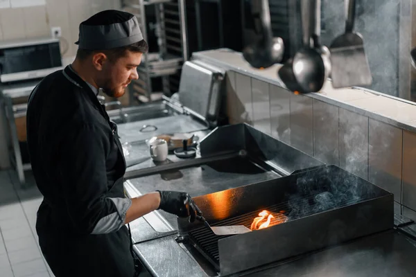 ホテルのレストランシェフのプロのキッチンがバーガーでパティを焼き — ストック写真