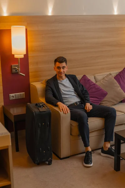 Een Man Met Een Koffer Zit Een Bank Een Hotelkamer — Stockfoto