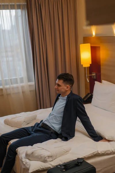 Man Met Koffer Zittend Bed Hotelkamer Tijdens Het Reizen Recreatie — Stockfoto