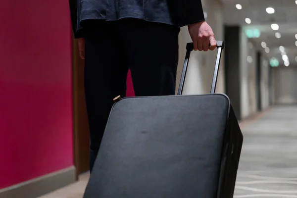 A man with a suitcase walks down the hotel corridor a back view of a businessman on trip