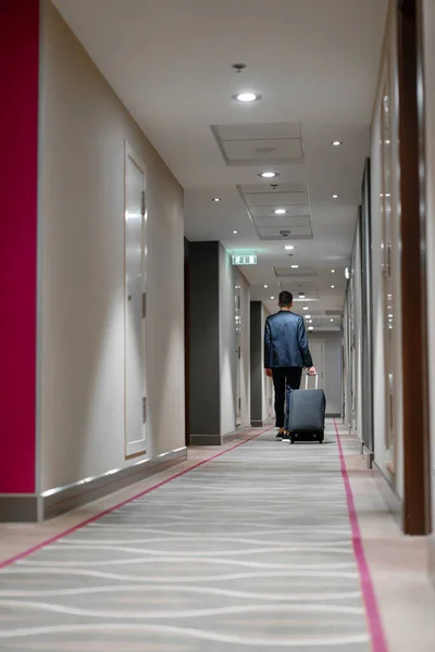 Mężczyzna Walizką Idzie Korytarzem Hotelowym Wsteczny Widok Biznesmena Podróży — Zdjęcie stockowe