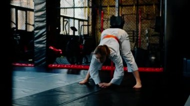 Kimonolu bir kadın olarak karate yapıyor. Hareketler yapıyor ve dövüş sanatlarında poz veriyor.