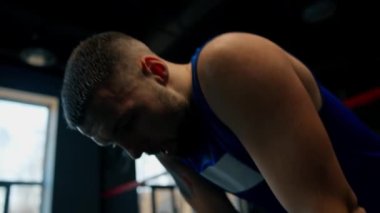 Spor kıyafetleri ve siyah boks eldivenleri giyerek spor salonunda sıkı antrenman yaptıktan sonra yorgun boksör.
