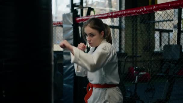 Girl Kimono Exercises Punching Bag Gym While Learning Karate Martial — Stock Video