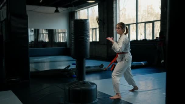 Girl Kimono Exercises Punching Bag Gym While Learning Karate Martial — Stock Video