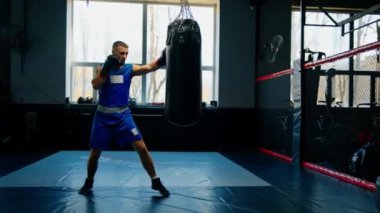 Bir boksör boks yaparken yumruklarını kum torbasına vurur.