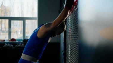 Spor kıyafetleri ve siyah boks eldivenleri giyerek spor salonunda sıkı antrenman yaptıktan sonra yorgun boksör.