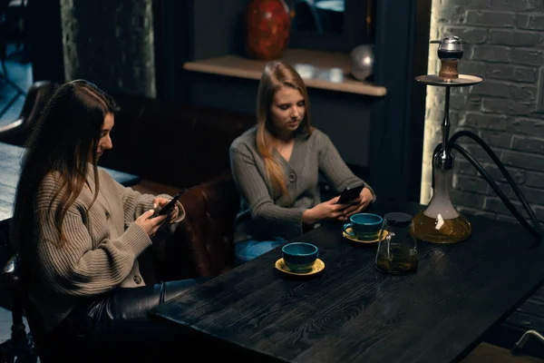 Zwei Junge Freundinnen Sitzen Entspannt Mit Telefonen Der Hand Der — Stockfoto