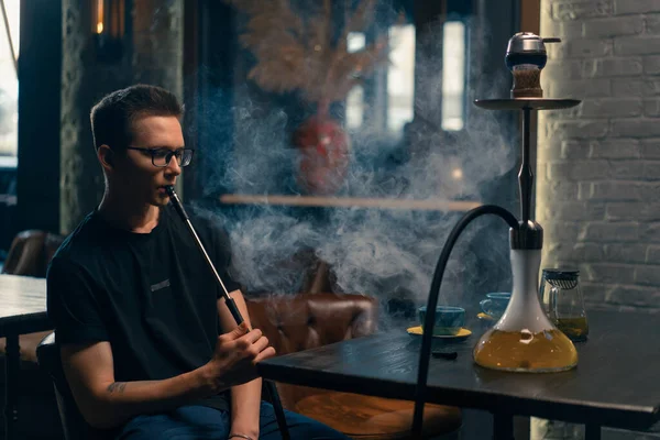 眼鏡の男煙伝統的なフカパイプ男Exhales厚い煙でフカフェやラウンジバー — ストック写真
