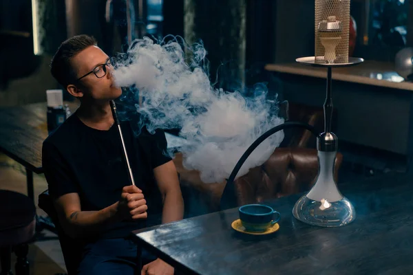 眼鏡の男煙伝統的なフカパイプ男Exhales厚い煙でフカフェやラウンジバー — ストック写真