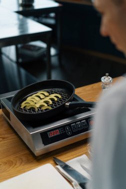 Profesyonel mutfak şefi tavada taze yeşil avokado pişiriyor. Kızarmış sebzeler sağlıklı gıda konsepti.