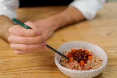 Profesyonel mutfak şefi taze pişmiş yulaf ezmesi kahvaltı konseptine karamelize elma parçaları koyar.