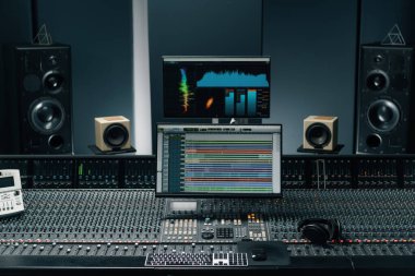 Ses dalgası ve ses ayarları olan bir ekran ile kayıt stüdyosu iki subwoofer ve karıştırma konsolu