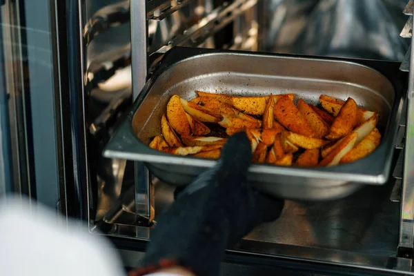 プロのキッチンシェフはオーブン調理プロセスから焼きジャガイモとベーキングトレイを取り出します — ストック写真