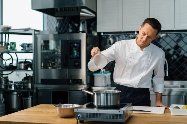プロのキッチンシェフが鍋料理に水を注ぐオートミール朝食健康的な食事のコンセプト — ストック写真