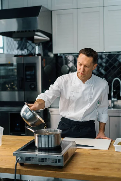 プロのキッチンシェフが朝食のための鍋にオートミールを注ぐ健康的な食事のコンセプト — ストック写真