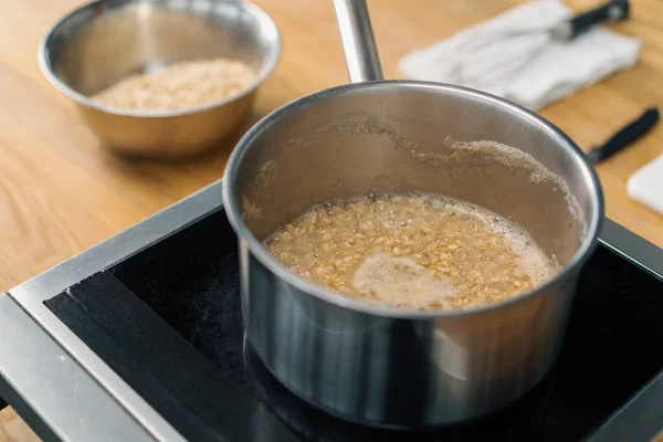 健康的な朝食キャセロールステンレス製のラドルストーブの上で沸騰したオートミールとお粥の完全な料理のコンセプト — ストック写真