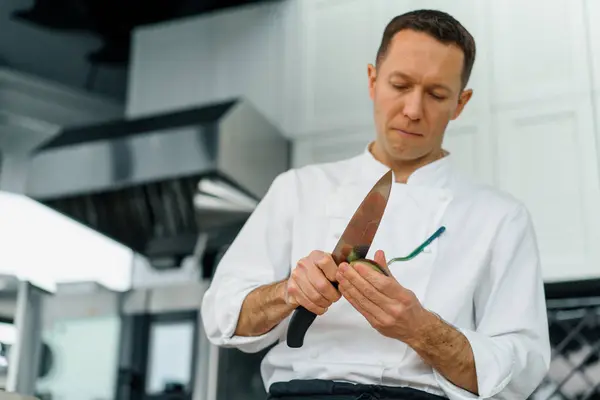 プロのキッチンシェフは ナイフで新鮮な緑のアボカドをきれいにすると肌のクローズアップを削除します — ストック写真