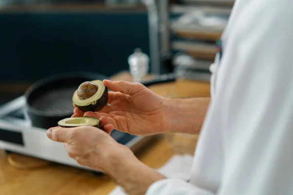 Professionele Keukenchef Reinigt Verse Groene Avocado Met Een Mes Verwijdert — Stockfoto