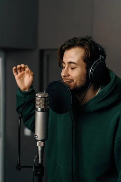 Rap singer with headphones microphone emotionally recording new song in professional recording studio