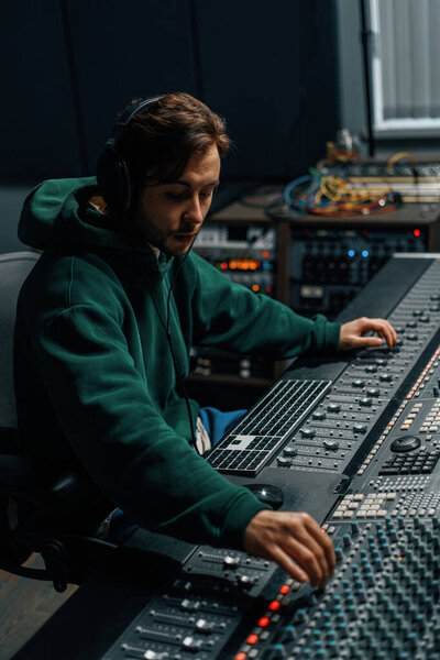 Звукорежиссер, работающий в музыкальной студии с мониторами и эквалайзером