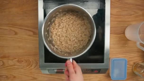 健康早餐砂锅不锈钢勺满粥煮燕麦片在炉子上烹调的概念 — 图库视频影像