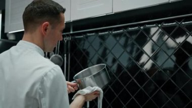 Mutfakta yemek pişirdikten sonra kirli bulaşıkları lavaboda yıkayan neşeli profesyonel şef.