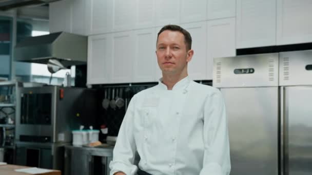 プロのキッチン笑顔と満足シェフ白いコートの横に立って腕の肖像画 — ストック動画