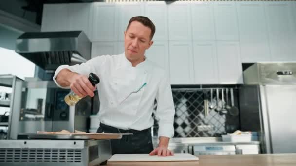 现代餐馆厨房里的一位专业厨师在新鲜的面包上洒香料 — 图库视频影像