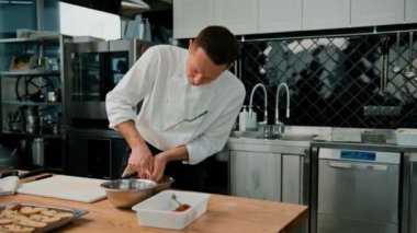 Profesyonel mutfak aşçısı mutfak hortumundan tabağa sos sıkıp sağlıklı besleniyor.