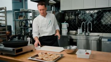 Profesyonel mutfak aşçısı mutfak malzemelerini tutar ve pişirme konseptine başlamadan önce onları kumaşla siler.