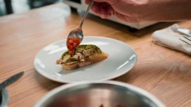 Profesyonel aşçı avokado ve domatesli tostu sağlıklı yemek kahvaltısı kavramının üzerine baharat döker.