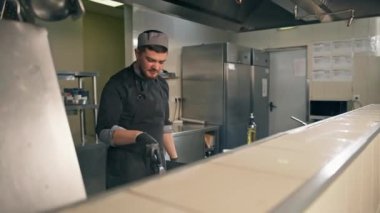 Otel restoranındaki profesyonel mutfak şefi hamburgerin üstünde köfte pişiriyor.