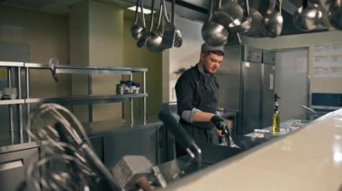 Otel restoranındaki profesyonel mutfak şefi hamburgerin üstünde köfte pişiriyor.