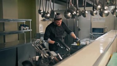 Otel restoranındaki profesyonel mutfak şefi hamburgerin üstünde köfte pişiriyor.