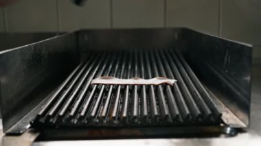 Otel restoranındaki profesyonel mutfak aşçısı yemek konsepti için ızgaraya domuz pastırması koydu.