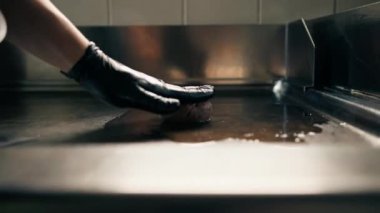 Restoranın mutfağında şef köfteleri ezmek için hazırlar ve köfteyi basınla ezer.